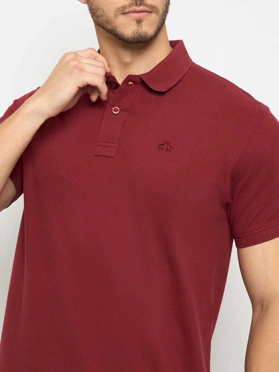 Man wears 98degreenorth Men's Maroon Solid Polo T-Shirt in cotton pique, touching the collar against a plain background.