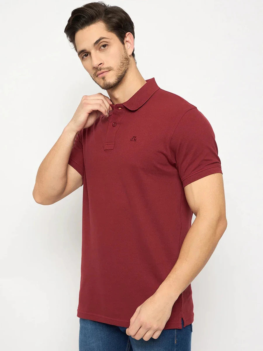 Man wears 98degreenorth Men's Maroon Solid Polo T-Shirt — Cotton Pique with blue jeans, standing against a white background.