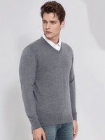 A man wears a 98degreenorth Men’s Medium Grey Merino Wool V-Neck Sweater over a white shirt and blue jeans.