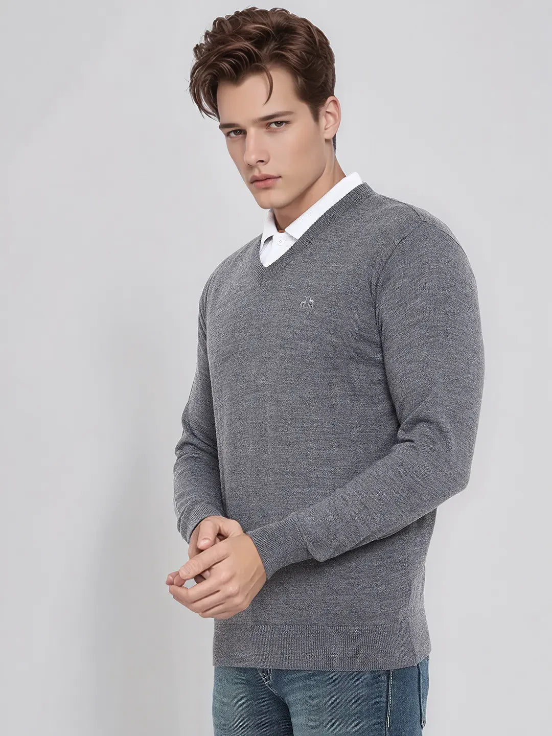 Man wears 98degreenorth Men’s Medium Grey Merino Wool V-Neck Sweater over a white shirt and blue jeans, plain background.