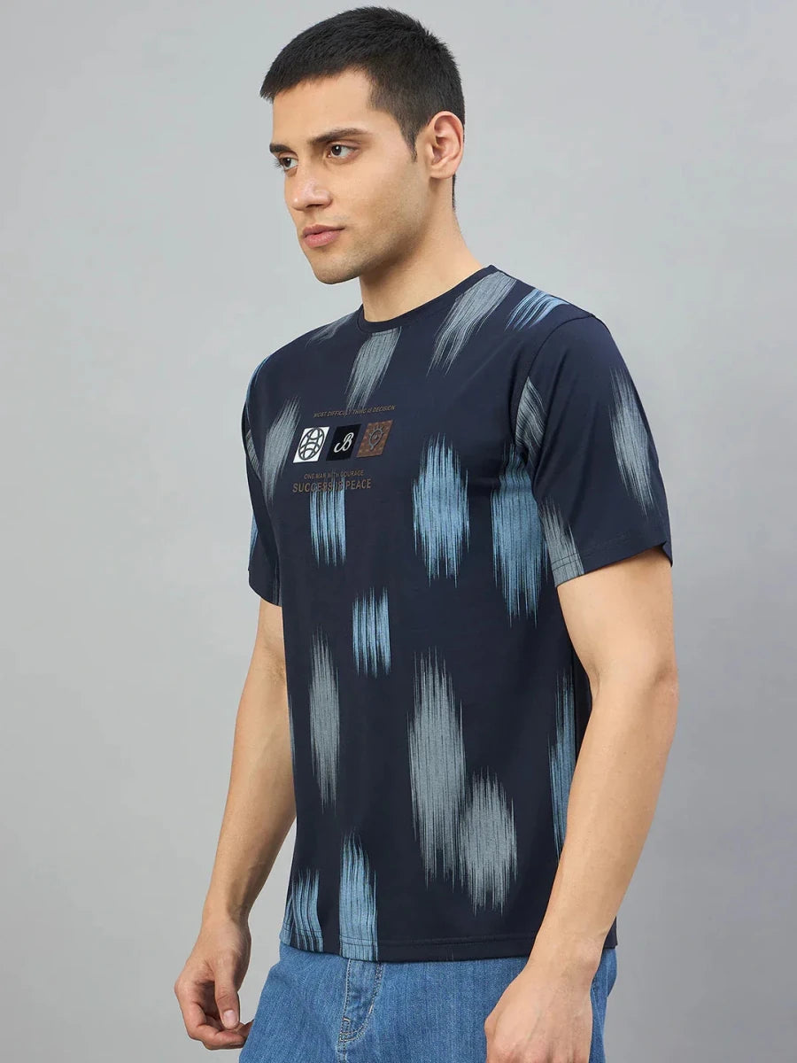 Man in 98degreenorth Men's Navy Abstract Ikat Print T-Shirt and light blue jeans, standing against a gray background.