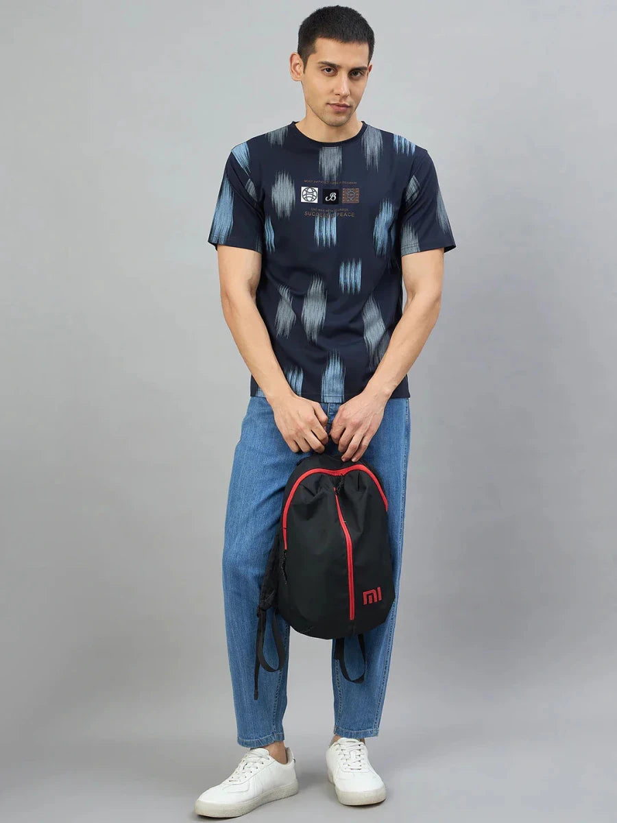 Man in a Men's Navy Abstract Ikat Print T-Shirt by 98degreenorth, blue jeans, and white sneakers holding a backpack.