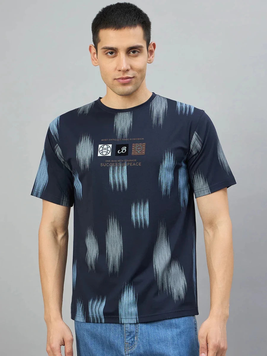 Man wears 98degreenorth Men's Navy Abstract Ikat Print T-Shirt with jeans, against a plain gray background.