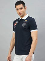 Man wears Men's Navy Aeronorth KC-767A Aviation Polo T-Shirt by 98degreenorth, with white collar and patches.