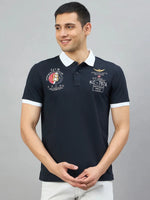 Smiling man wears a Men's Navy Aeronorth KC-767A Aviation Polo by 98degreenorth, against a gray background.