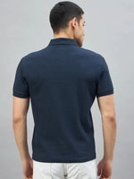 A man in a 98degreenorth navy popcorn knit quarter zip polo stands with his back to the camera.