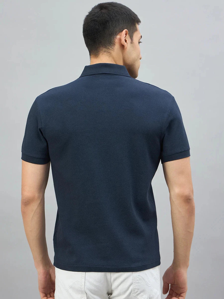 A man in a 98degreenorth navy popcorn knit quarter zip polo stands with his back to the camera.