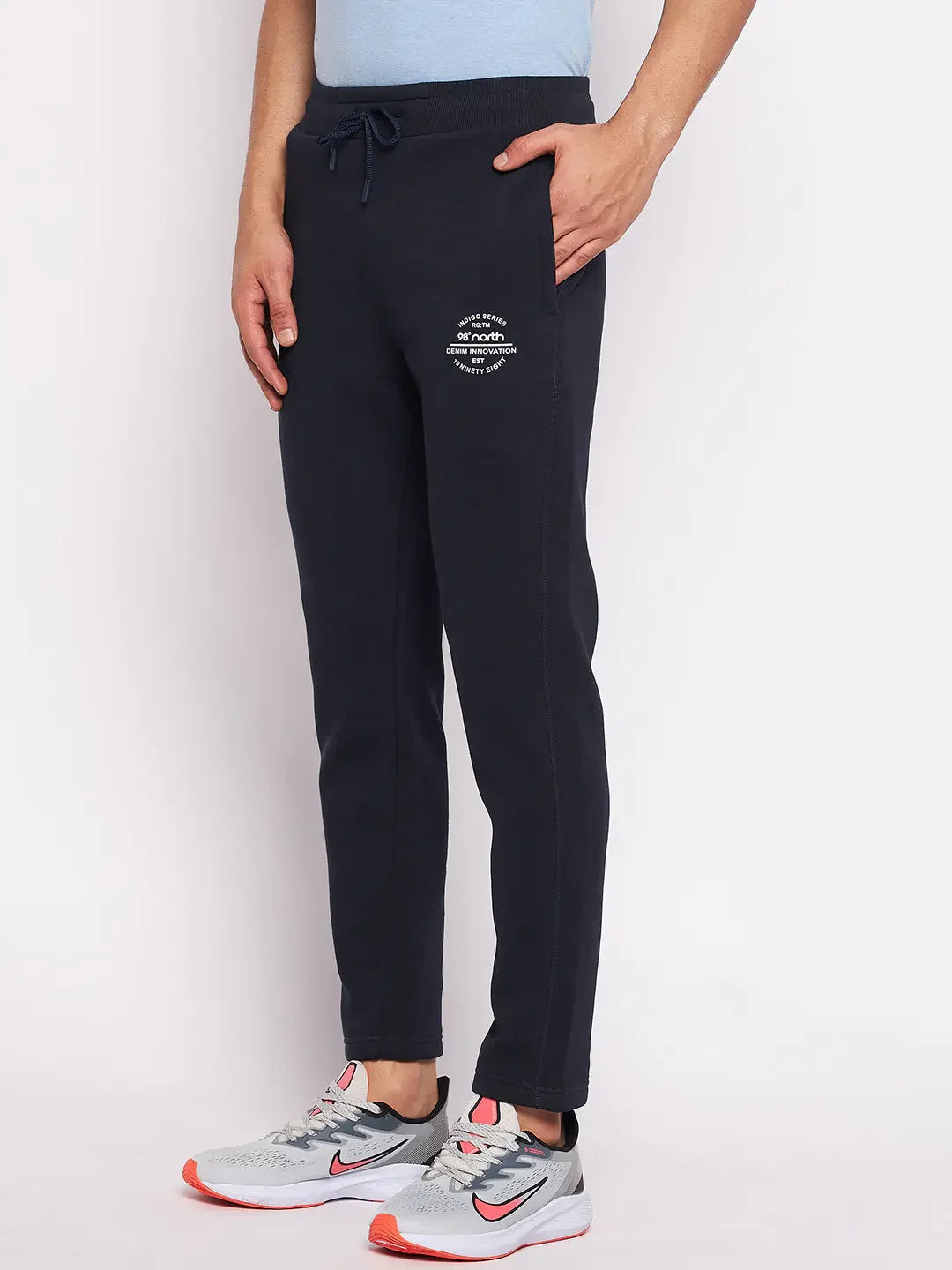 Model wears 98degreenorth Men’s Navy Fleece Trackpants – Classic Warm Joggers with gray sneakers, one hand in pocket.