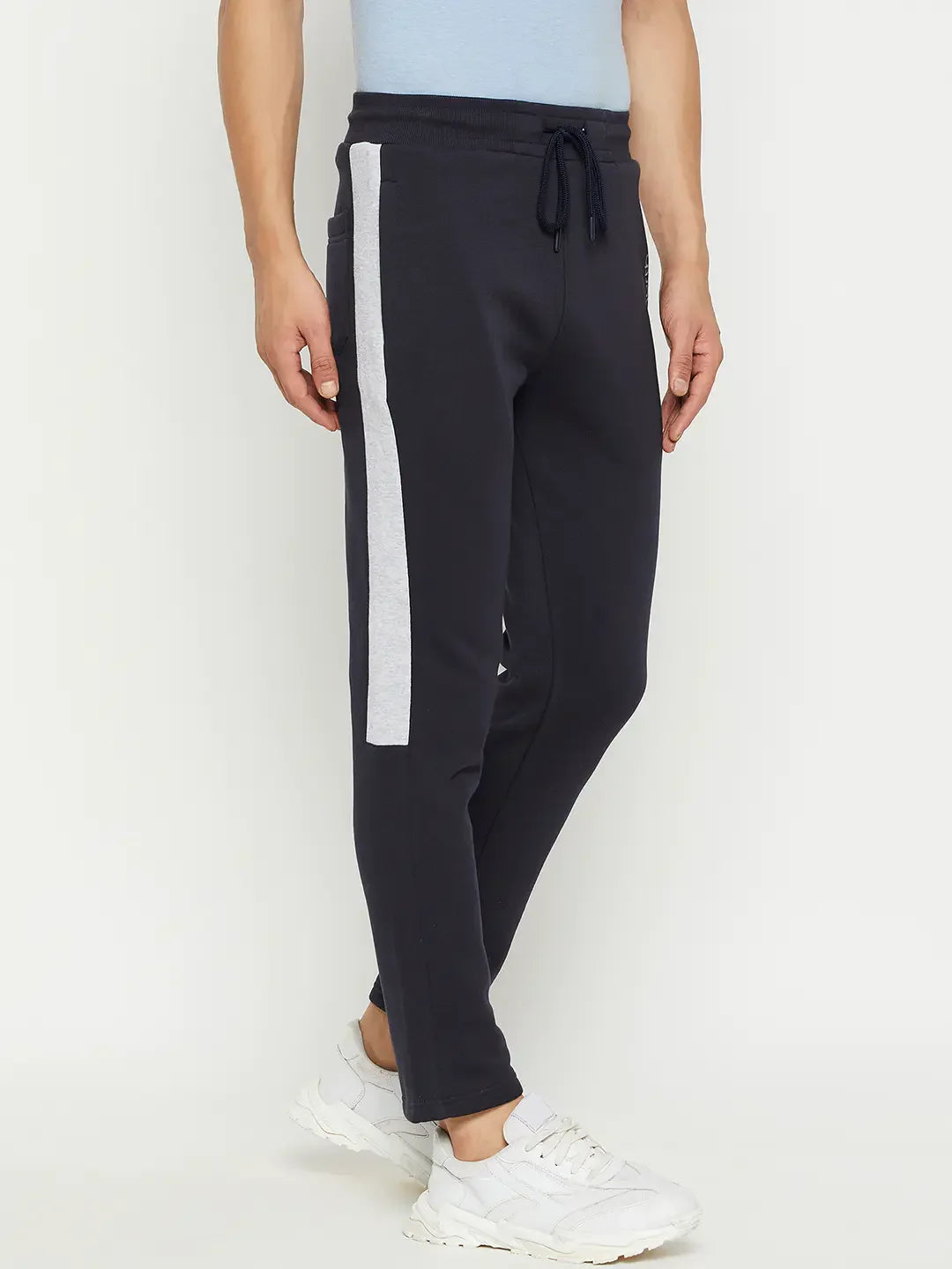 Man wearing 98degreenorth Men’s Navy Fleece Trackpants with contrast side stripe and white sneakers, against a plain background.
