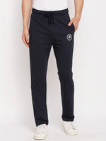 Man in 98degreenorth Men's Navy French Terry Lycra Trackpants, white sneakers, and shirt against a plain background.