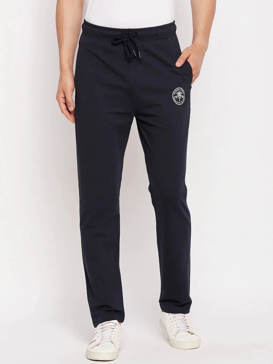 Man in 98degreenorth Men's Navy French Terry Lycra Trackpants, white sneakers, and shirt against a plain background.