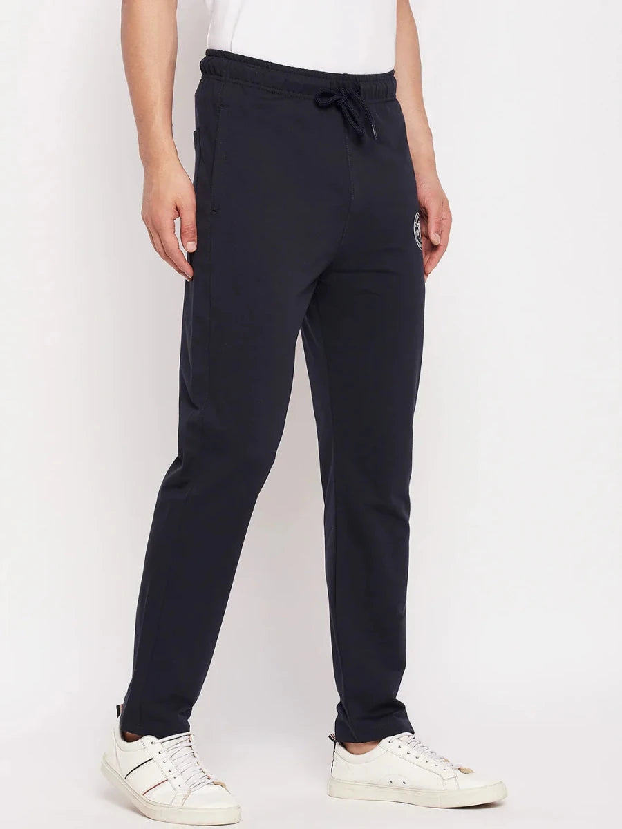 A man in 98degreenorth Men's Navy French Terry Lycra Trackpants, perfect for summer athleisure and smart casual wear.