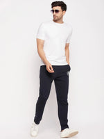 Man in 98degreenorth Navy French Terry Lycra Trackpants, white tee, sunglasses & sneakers against plain background.