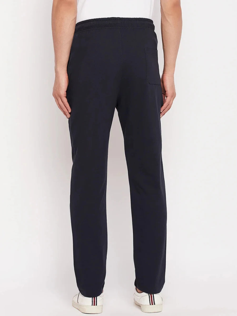 Man in 98degreenorth Men's Navy French Terry Lycra Trackpants & white sneakers, shown from the back against plain backdrop.