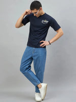 Man in 98degreenorth Men's Navy Graphic Oversized T-Shirt — GOAT Back Print, blue jeans, white sneakers, posing coolly.
