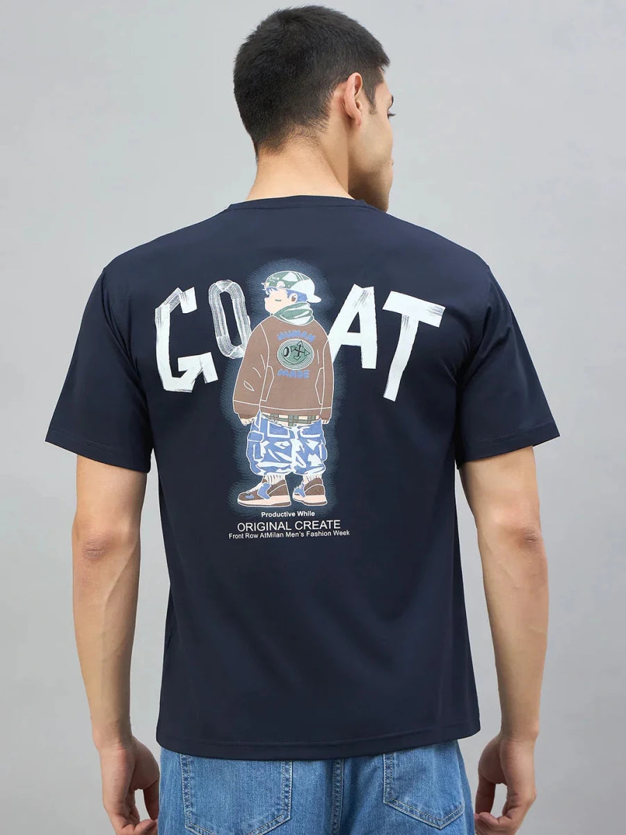 A man in a 98degreenorth navy oversized T-shirt with GOAT back graphic stands against a plain background.