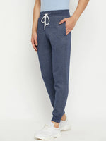 A person in 98degreenorth Men’s Navy Jaspe Fleece Trackpants, a light blue shirt, and white sneakers stands against a plain background.