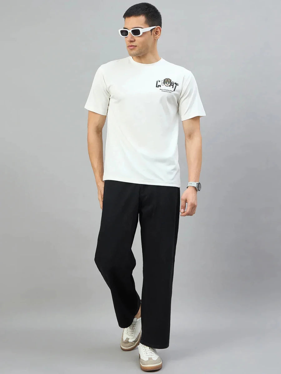 Man in white sunglasses, 98degreenorth Men's Off-White Graphic Oversized T-Shirt, black pants & white sneakers by gray background.
