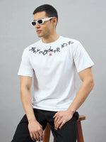Man wearing 98degreenorth's Off-White Graphic Oversized T-Shirt sits on a stool against a plain gray background.