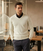 A man wears the 98degreenorth Off-White Merino Wool V-Neck Sweater, a soft neutral pullover for elegant layering.