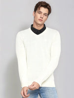 A man wears the 98degreenorth Men’s Off-White Merino Wool V-Neck Sweater with blue jeans against a gray backdrop.