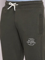 Close-up of 98degreenorth Men’s Olive Fleece Trackpants with white drawstring and printed text by the left pocket.