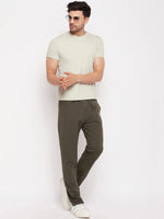 Man in a light beige tee, 98degreenorth olive French terry Lycra trackpants, white sneakers & sunglasses on white bg.