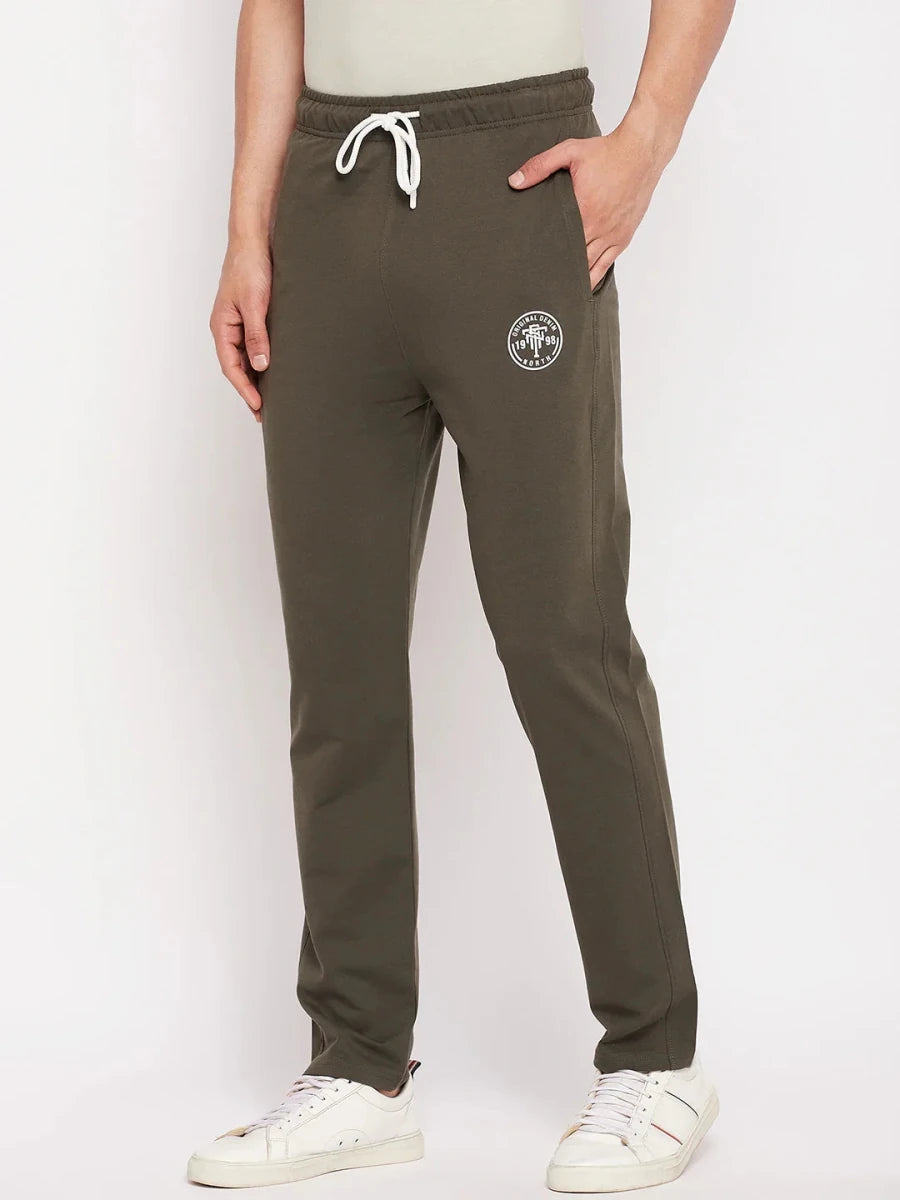 Person in 98degreenorth Men's Olive French Terry Lycra Trackpants with white sneakers, against a white background.