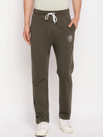 A person in 98degreenorth Men's Olive French Terry Lycra Trackpants, with white drawstrings and sneakers, hands in pockets.