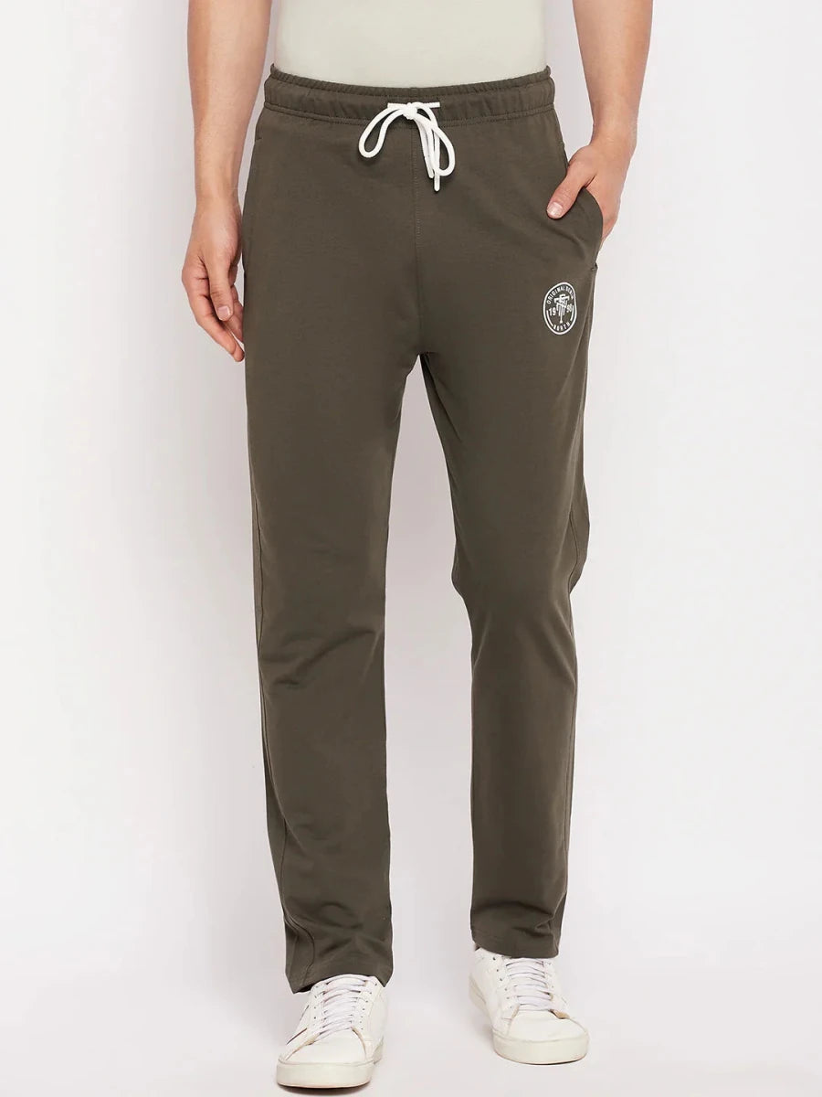 A person in 98degreenorth Men's Olive French Terry Lycra Trackpants, with white drawstrings and sneakers, hands in pockets.
