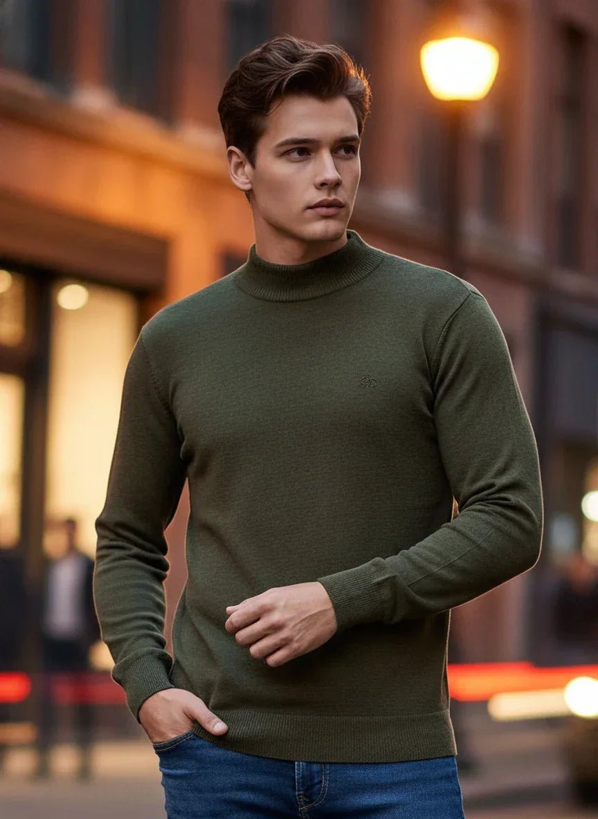 A young man in India wears a 98degreenorth Men’s Olive Merino Wool Turtle Neck Sweater with city lights behind him.