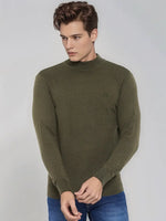 A man wears a 98degreenorth Men’s Olive Merino Wool Turtle Neck Sweater and blue jeans, standing against a light gray background.