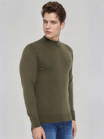 A man wears the 98degreenorth Men's Olive Merino Wool Turtle Neck Sweater, paired with blue jeans, on a gray backdrop.