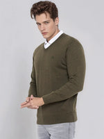 Man wears 98degreenorth Men’s Olive Merino Wool V-Neck Sweater over white shirt and light jeans against plain backdrop.