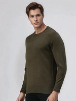 A man models the 98degreenorth Men’s Olive Merino Wool Sweater with black pants against a light gray background.