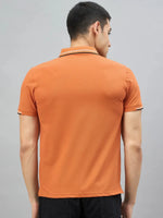 Man in a 98degreenorth Handmade Series Men's Orange Polo T-Shirt with contrast tipping, seen from the back on grey.
