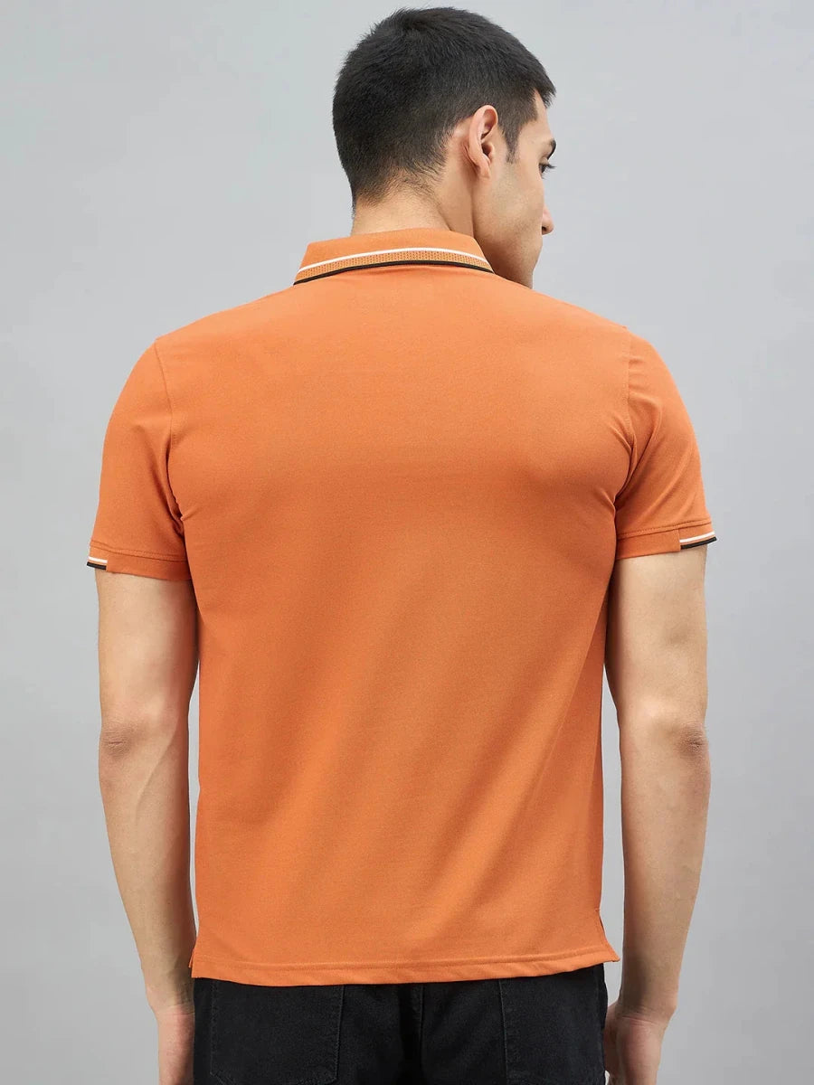 Man in a 98degreenorth Handmade Series Men's Orange Polo T-Shirt with contrast tipping, seen from the back on grey.