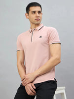 A man in a 98degreenorth Men's Pink Polo T-Shirt sits on a white stool against a plain grey background.