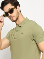 Man in a 98degreenorth Men's Pista Green Polo T-Shirt, pure cotton pique knit, posing stylishly against a plain background.