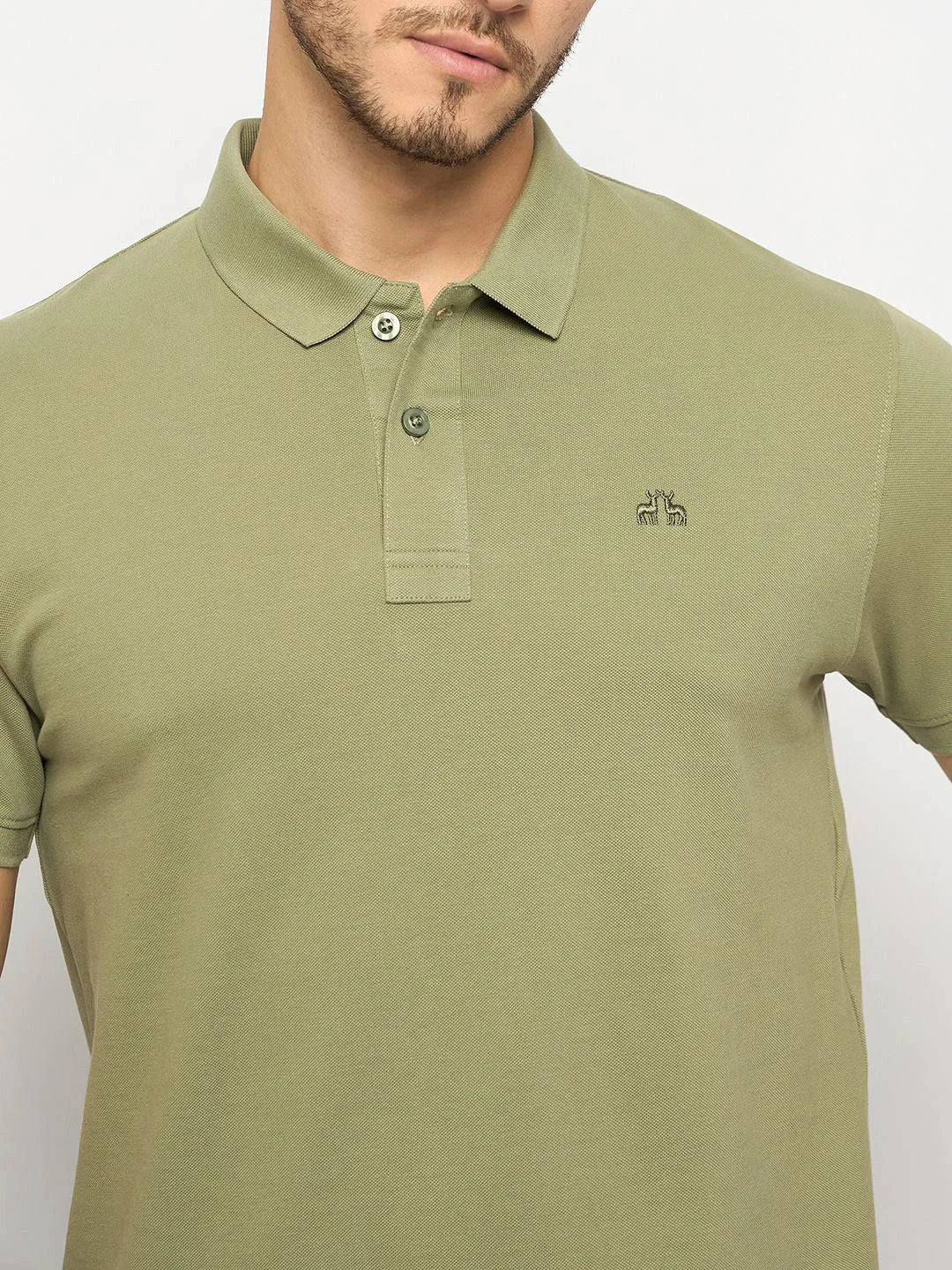 Man wears 98degreenorth Men's Pista Green Polo T-Shirt—pure cotton pique knit with embroidered giraffe logo.