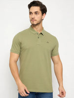 Man in a men's Pista Green Polo T-Shirt by 98degreenorth and blue jeans, posing against a plain white background.