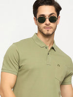 Man in 98degreenorth Men's Pista Green Polo T-Shirt with chest pocket poses against a light background.
