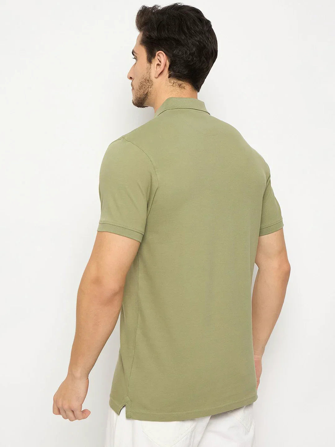 Man wears 98degreenorth Men's Pista Green Cotton Pique Polo with chest pocket, back facing camera against plain background.