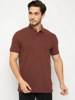 Man in 98degreenorth Men's Rust Solid Polo T-Shirt—Cotton Pique, paired with black pants, on white background.