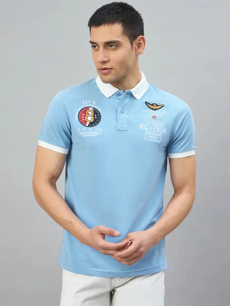 Man in Men's Sky Blue Aeronorth KC-767A Aviation Polo T-Shirt by 98degreenorth, ideal for aviation fans, gray backdrop.