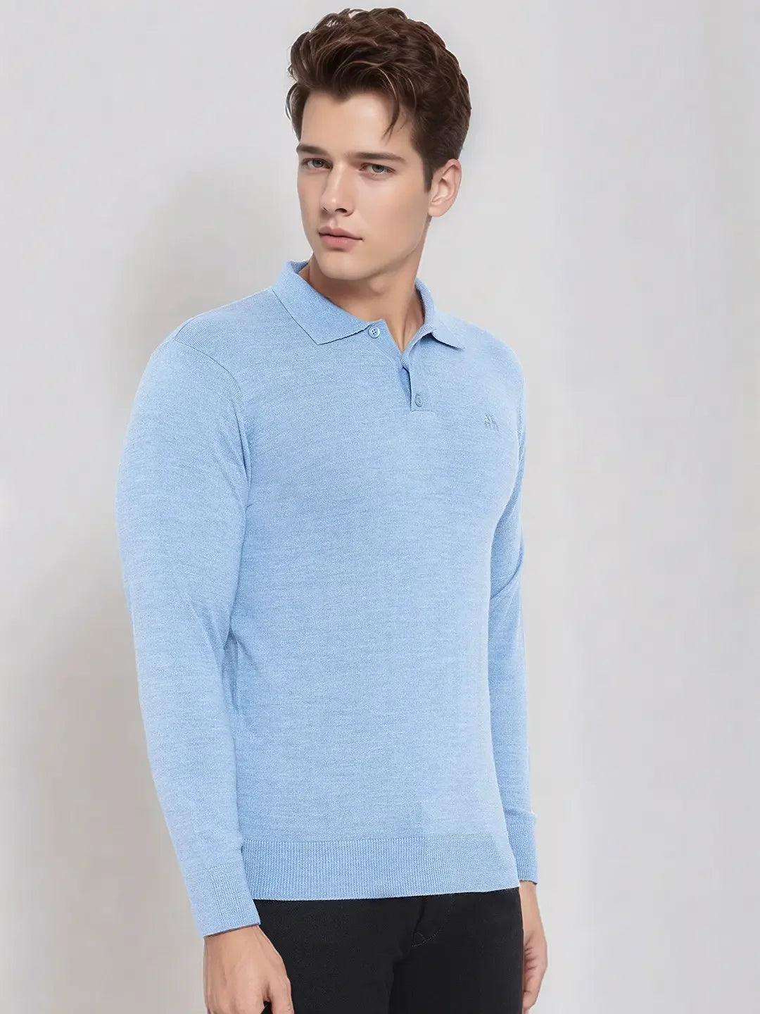 A man wears a 98degreenorth Men’s Sky Blue Merino Wool Polo Sweater with black pants against a plain light background.