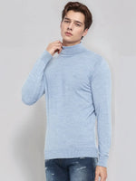 Man in 98degreenorth Men’s Sky Blue Merino Wool Turtle Neck Sweater and jeans, against a plain light background.