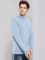 Man in a 98degreenorth Men’s Sky Blue Merino Wool Turtle Neck Sweater and blue jeans on a plain light background.