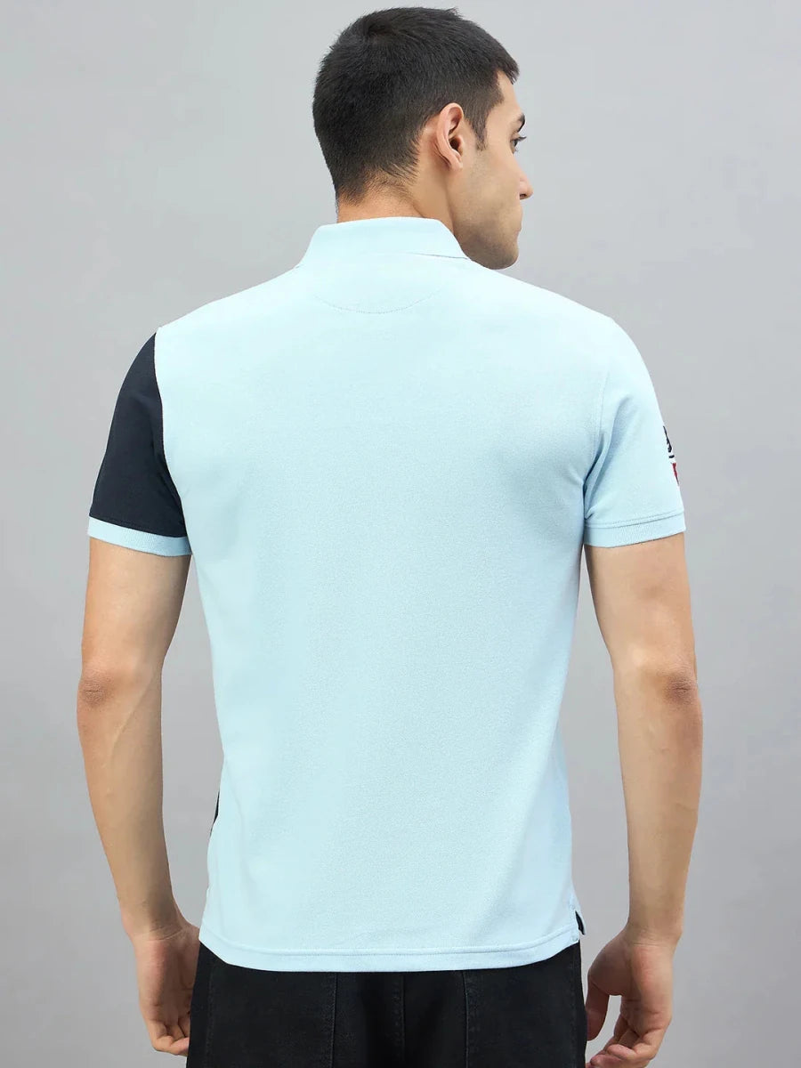 A man in a 98degreenorth Men's Sky Blue & Navy Colour Block Polo, seen from the back against a gray background.