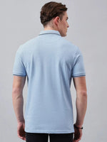 A man seen from behind wears the 98degreenorth Men's Sky Blue Solid Polo T-Shirt against a plain gray background.
